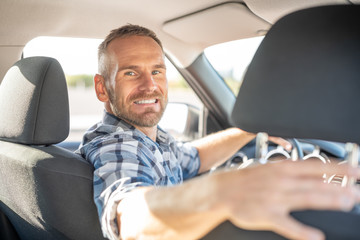 Attractive man driving a car on a clear day. Buying or renting a car.