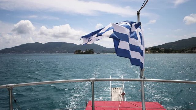 A shot of the Greek flag sucking in the wind on a moving boat. Beautiful weather azure sky and sun.