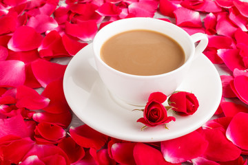 Red rose petals background and a cup of coffee. side view.