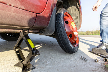 the driver changes the punctured wheel to a temporary one among the road, close-up