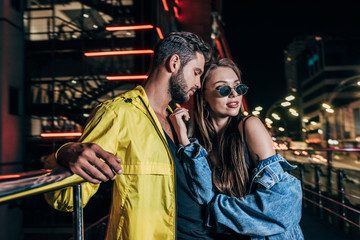 Fototapeta na wymiar handsome boyfriend and attractive girlfriend in denim jacket hugging in night city