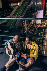 Obraz na płótnie Canvas high angle view of handsome boyfriend with plastic cup and attractive girlfriend playing acoustic guitar in night city