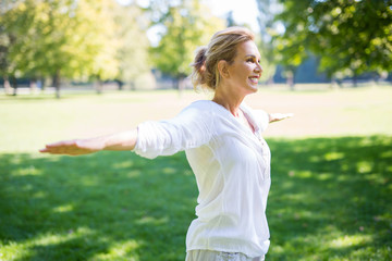 Attraktive ältere Frau macht Übungen im Park  - 293362615