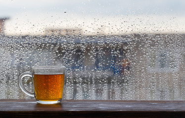 cup of tea on  background of  window with raindrops at sunset