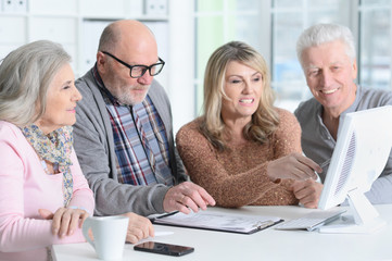 Portrait of two senior couples sitting at table and working