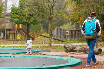 Mother and daughter walking through children playground with trampolines.