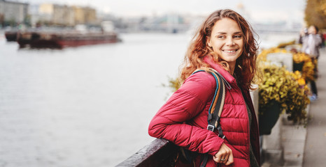 Fototapeta premium Portrait Beautiful charming young funny happy girl with red curly hair and on the promenade in the autumn park