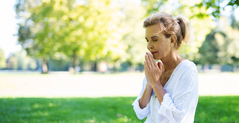 Positive Frau im mittleren Alter macht Meditationsübungen im Park 
