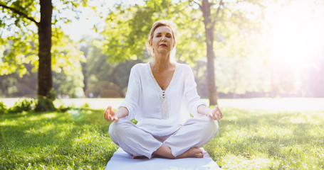 Frau macht Meditationsübungen im Park 