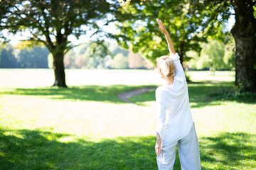 Frau im mittleren Alter macht Übungen im Park, Yoga und Meditation 