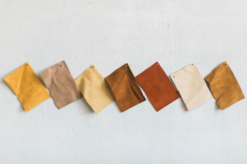 brown suede leather cowhide swatches on white wall, copy space