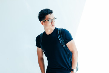 Young handsome asian men wearing casual plain shirt and backpack on white background at day in Sai Gon city, Vietnam
