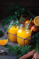 Healthy food. Carrots and carrot juice with orange in a glass jar in a metal basket on a dark...