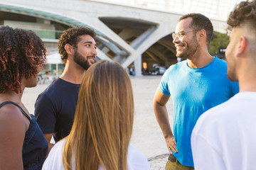 Diverse group of friends meeting in city square and chatting. Mix raced men and women standing in...