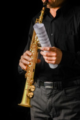 Fototapeta premium soprano saxophone in hands on a black background