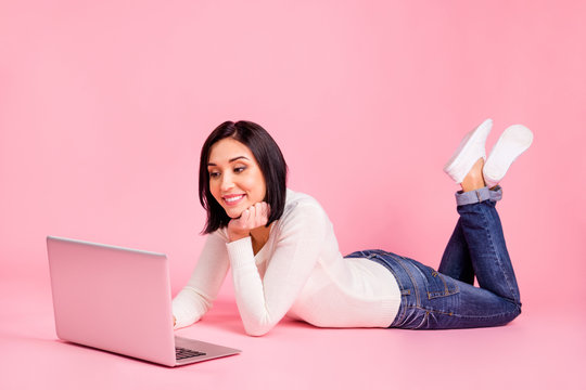 Full body photo of charming lady lying floor speaking skype with relatives wear white pullover and jeans isolated pink color background