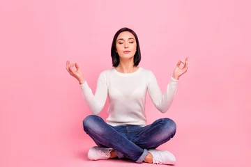 Zelfklevend Fotobehang Full length photo of charming lady sitting on floor relaxed on yoga lotus position wear white pullover and jeans isolated pink color background © deagreez