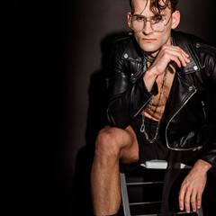 brutal man in leather jacket sitting on black