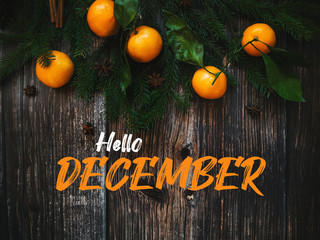 text Hello December on a wooden background with fir branches and mandarins © alexkoral