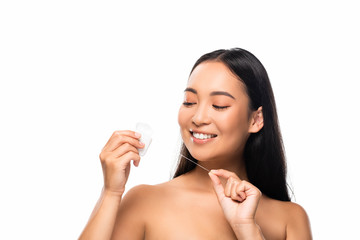 smiling asian naked woman looking at dental floss isolated on white