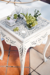 on a decorative table an album for notes, two glasses, a bouquet in a glass, an open box, a candle in a glass