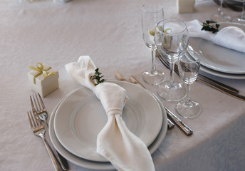table setting: plates, forks, knives, knotted napkin, glasses, small gift box