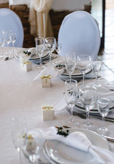 table setting: plates, forks, knives, knotted napkin, glasses, small gift box