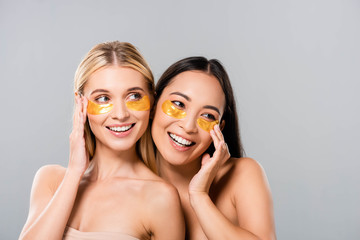 smiling beautiful asian and european naked girls with eye patches isolated on grey