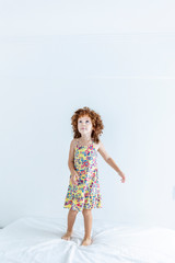 Beautiful girl playing and jumping on bed having a sleepover