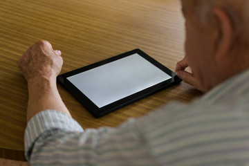 Elderly man is using a digital tablet at home