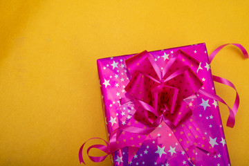 Pink color christmas gift box on yellow color background, copy space banner