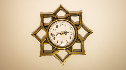 A white wall clock shaped like a golden lotus flower.