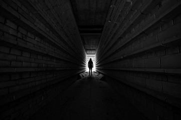 Person standing in light at the end of tunnel, silhouette