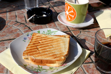 Cheese toast, drinks and cigarette in a cafe outdoor. Selective focus.