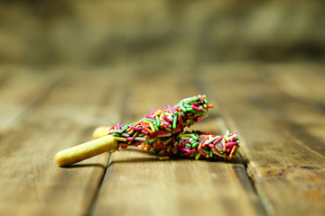 Biscuit stick bread with sweet colorful chocolate isolated on wood background