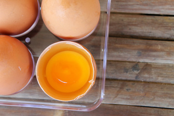 top view of broken eggshell with yellow yolk near eggs in plastic box