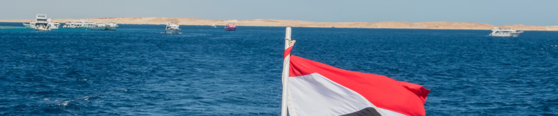 Egypt national flag waving on the wind of blue sky background.