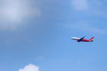 Fototapeta na wymiar airplane flying in blue sky with small clouds