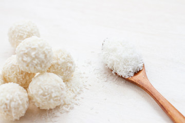 Fototapeta na wymiar white round candies with coconut flakes and wooden spoon with coconut flakes