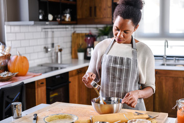 African american woman preparing pumpkin pie for holidays