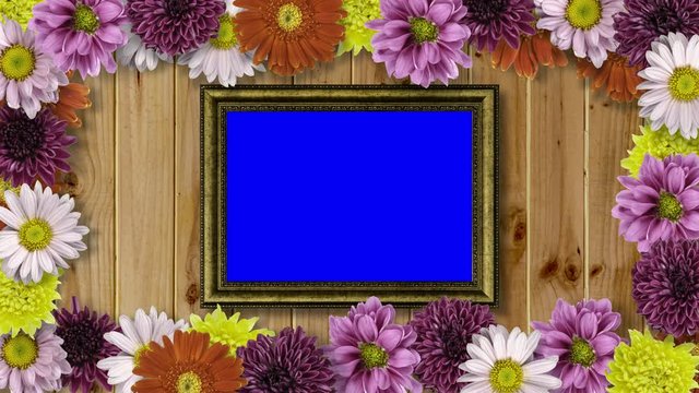 Picture frame with blue screen and colourful flowers on wooden background