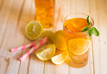 Glasses of ice tea with lemon slices and mint on wooden background