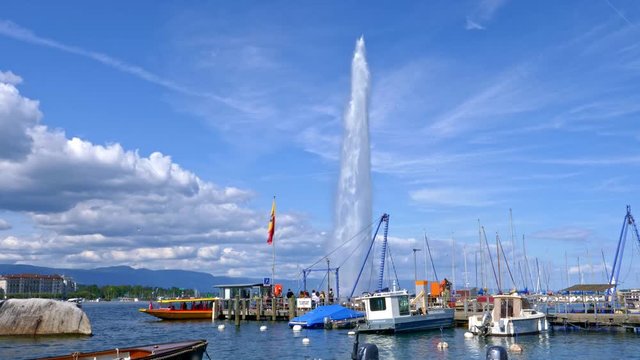 Lake Geneva (Switzerland) in the foreground a small port with several small boats and the water jet behind it.