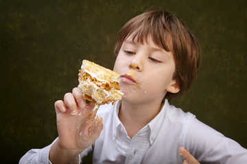 Little boy eating a cake while sitting at the table