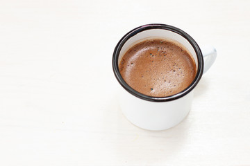 freshly brewed coffee in a white metal mug on a white table
