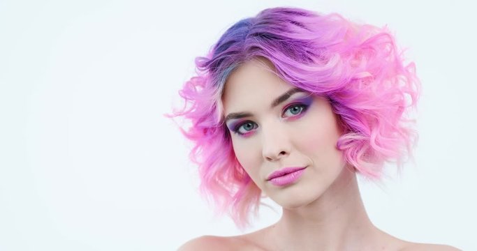Stylish woman with fashion hairstyle. Closeup portrait of a fashion model with bright purple hair. Beauty face with a pink makeup. Fashionable girl.  Woman turns her head  and looks to the camera.