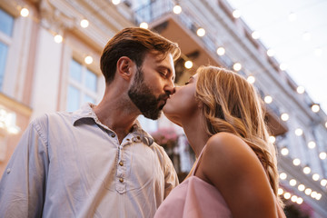 Loving couple walking by street outdoors kissing.