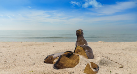 Pollution from a broken glass bottle lying on a beach