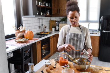 Fototapeta na wymiar African american woman preparing pumpkin pie for holidays