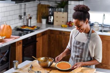 African american woman preparing pumpkin pie for holidays